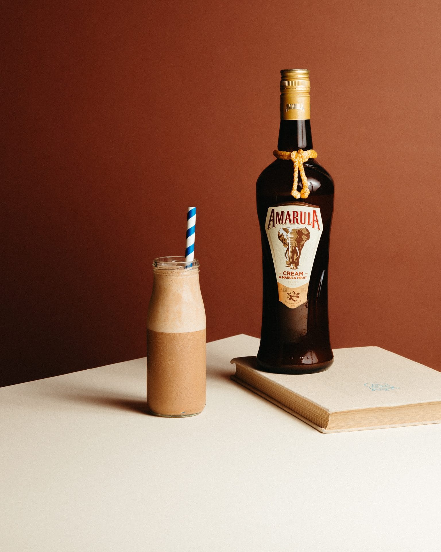 Butelka Amarula i koktajl w ciepłej brązowo-kremowej scenografii